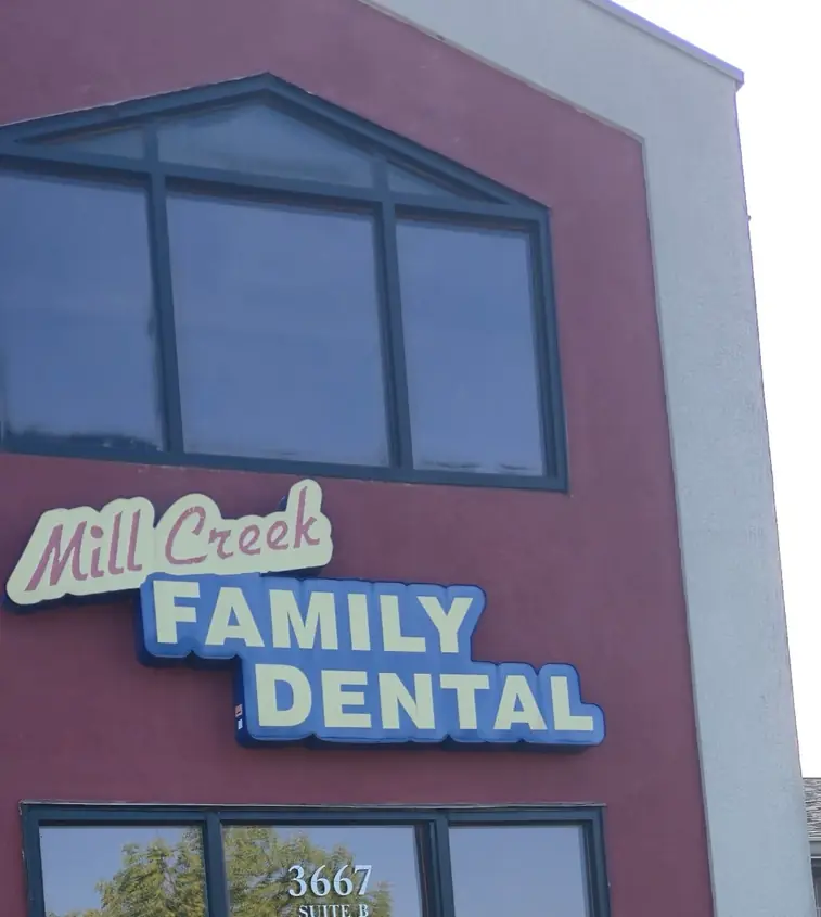 The Mill Creek Family Dental sign on the maroon facade above the Suite B door at 3667 Braddock Drive